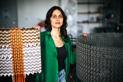 Alina Tenser wears a green shirt and stands with her sculptures in a studio at Lehigh University.