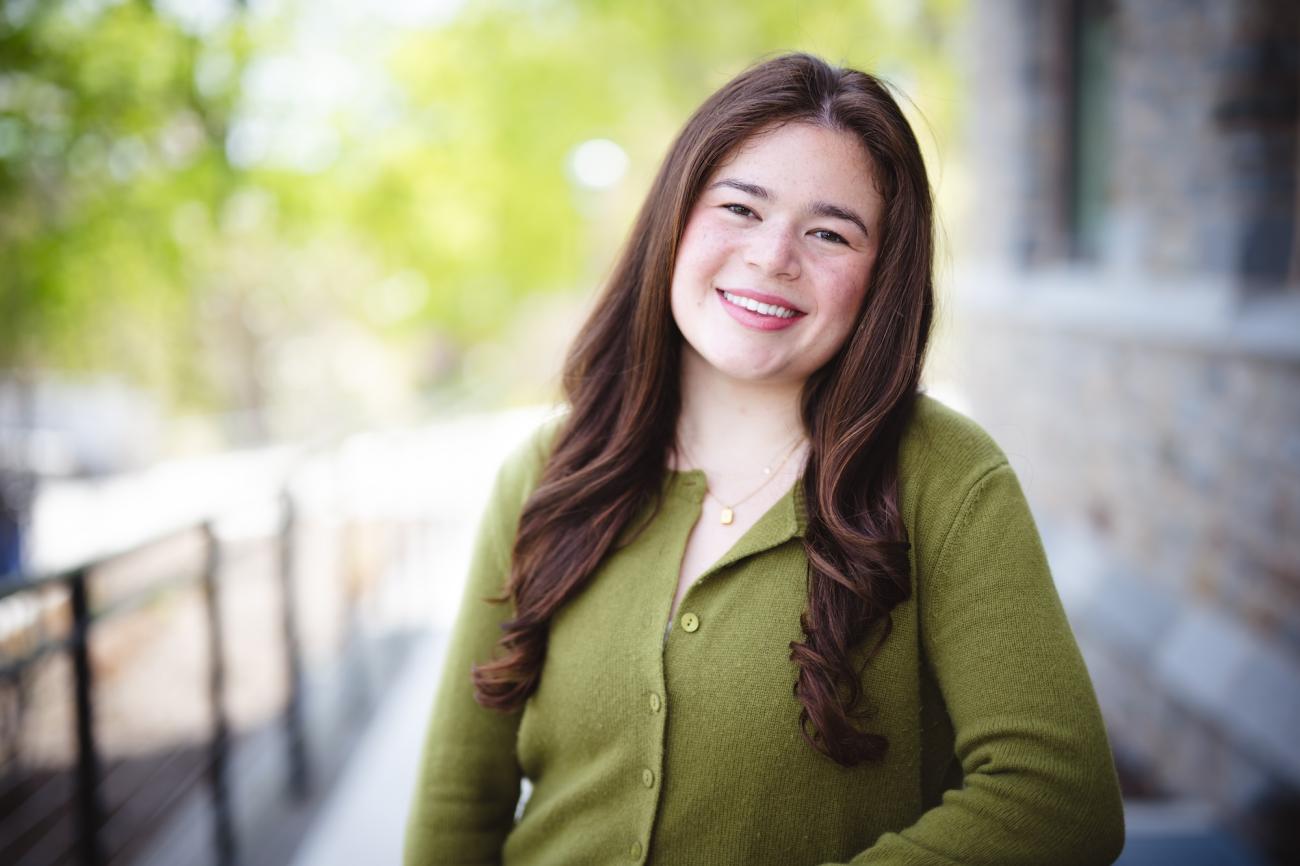 Rachel Gruber stands outside for a portrait in a green cardigan. 