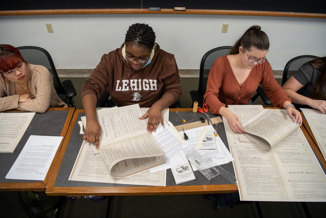 Students learn book binding in a classroom.