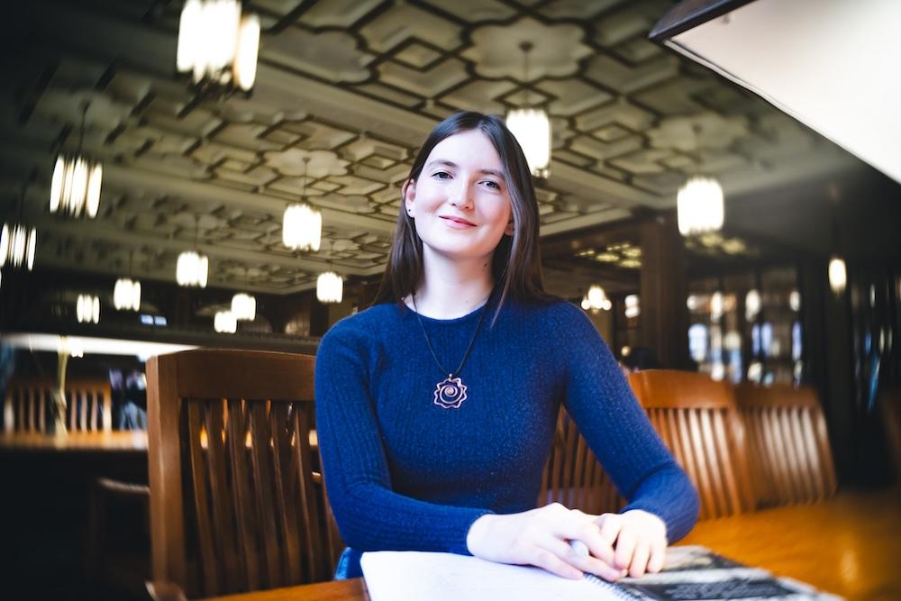 Jordan Ho sits in Linderman Library at a desk and poses for a portrait.