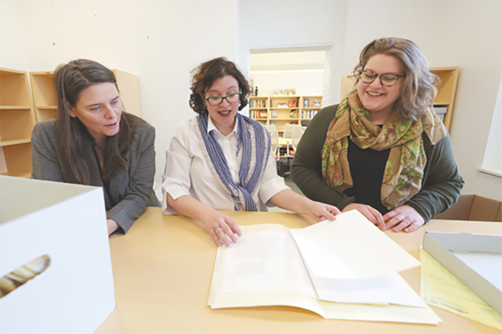 Mary Foltz, Suzanne Edwards and Sam Sorensen examine a document
