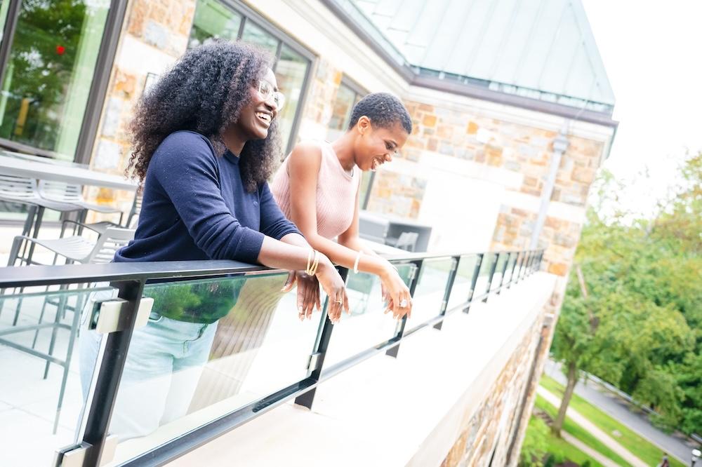 Lya Joseph ‘25 ‘26G and Emmanuella Agyemang ‘26 stand on the upper balcony of the university center.