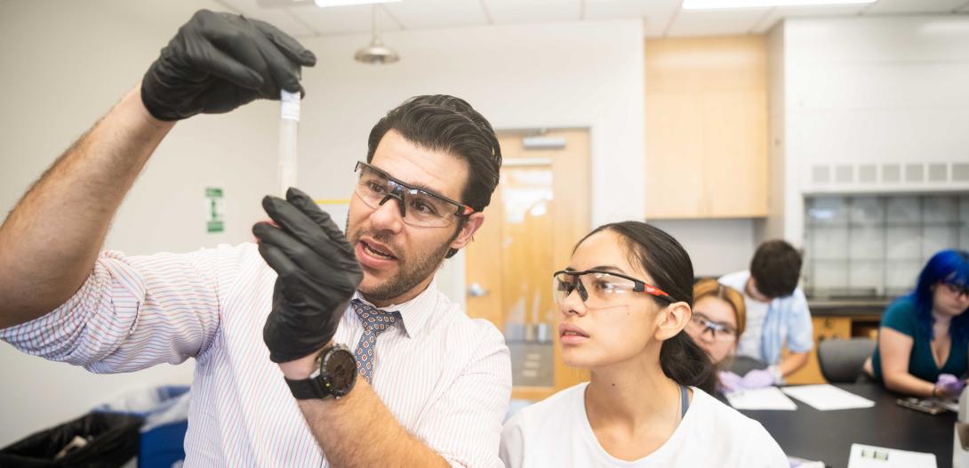 Lorenzo Servitje holds a pipette in a lab and examines it.